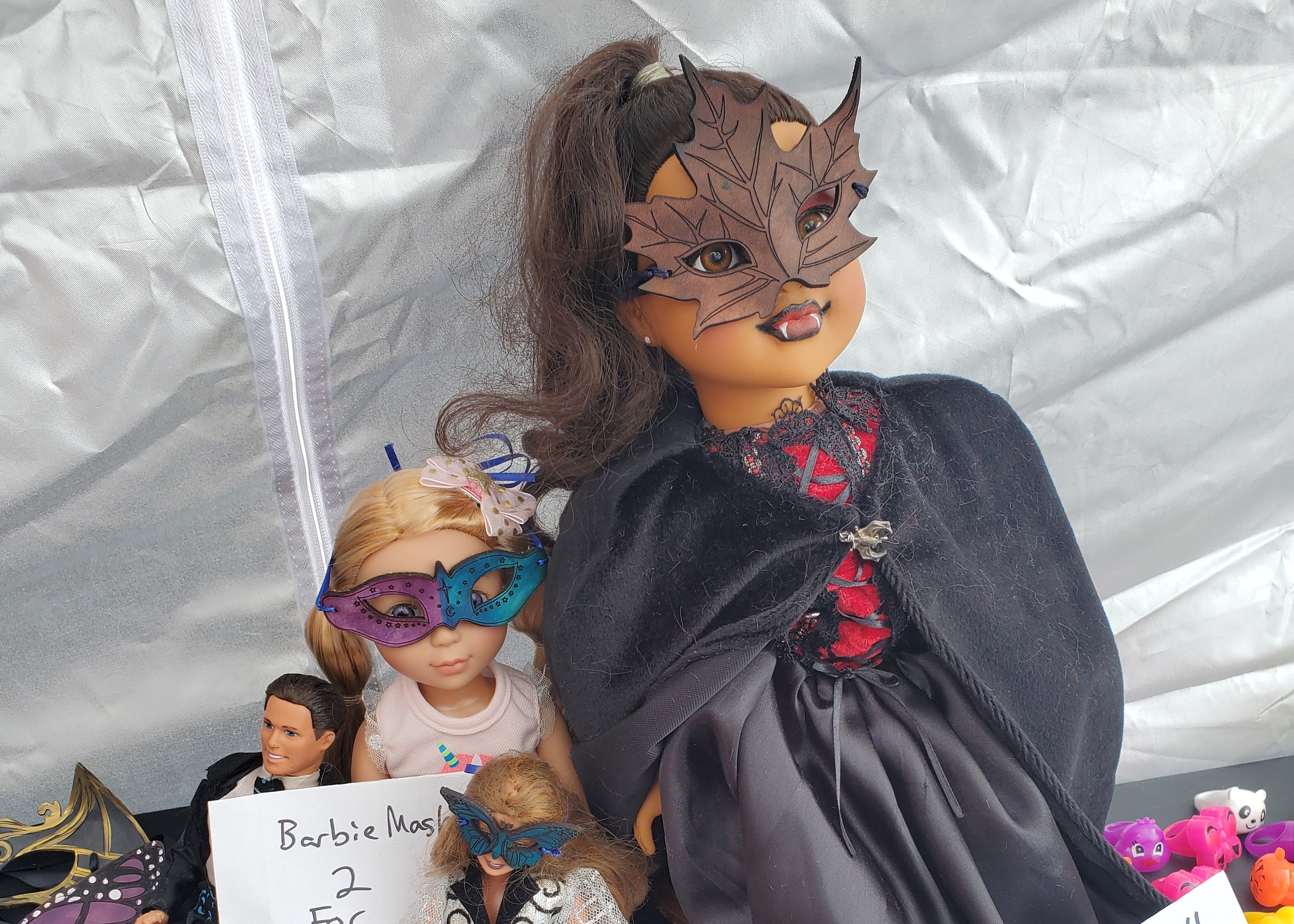 Photo of two dolls, 18 inch, and barbie, wearing masquerade masks.