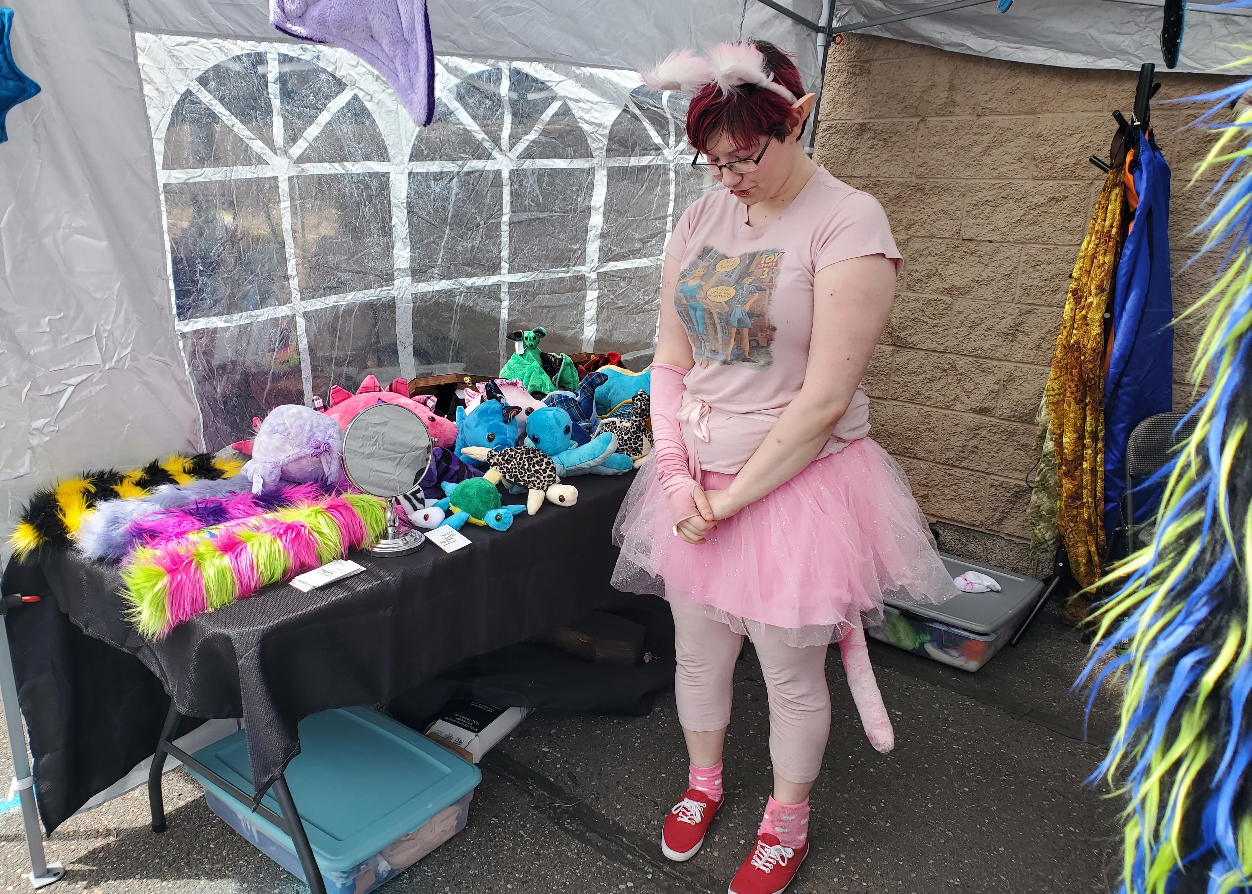 Photo of vendor in a pink tutu and cat ears/tail, at a booth.
